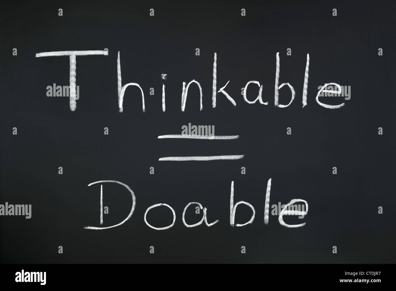 Las palabras "pensable = factible" escrita en una pizarra. Un aspecto conceptual en el pensamiento positivo. Foto de stock