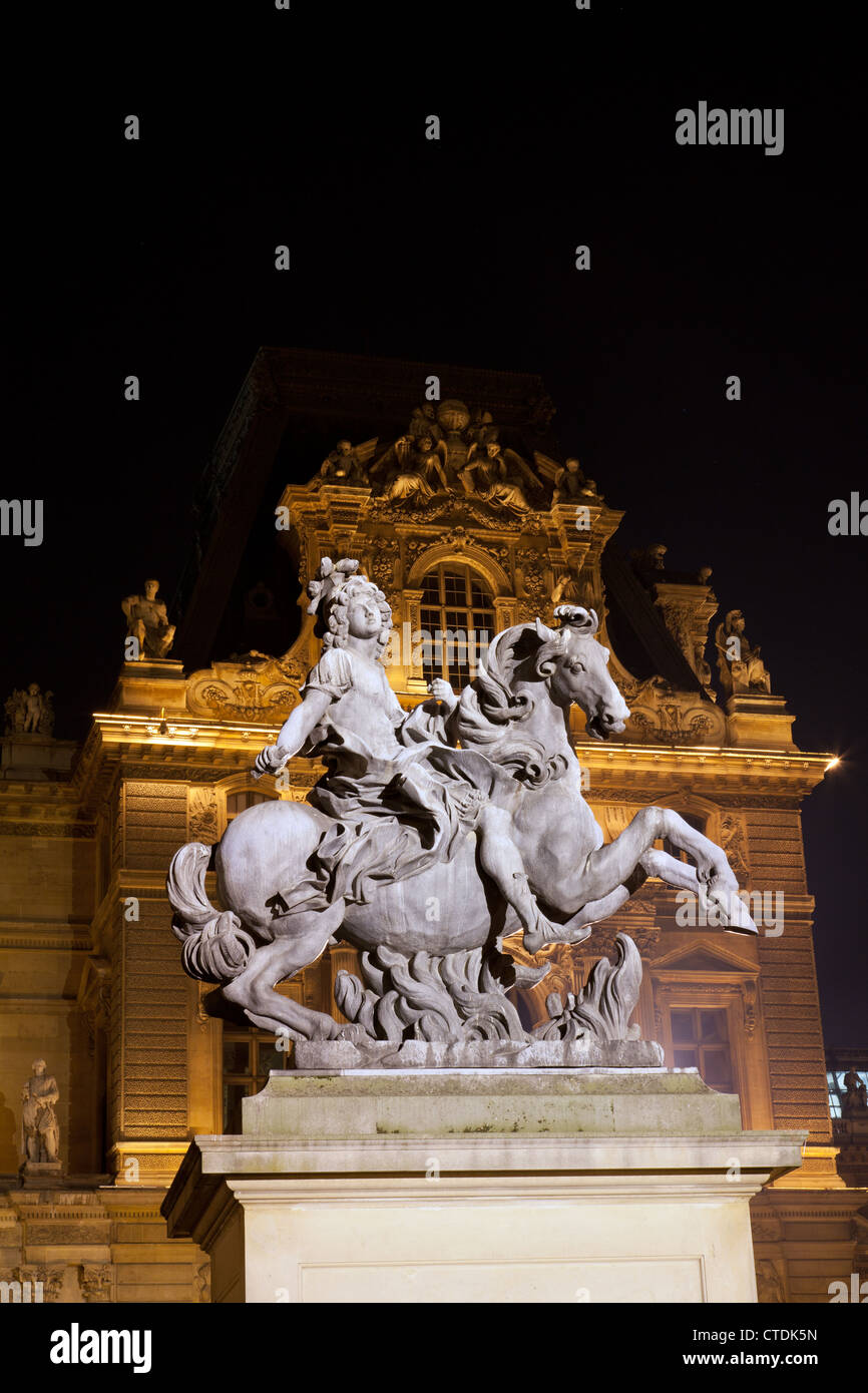 La estatua de Luis XIV (Cour Napoleón du Louvre) por Bernini en el patio del Louvre, iluminada por la noche. Foto de stock