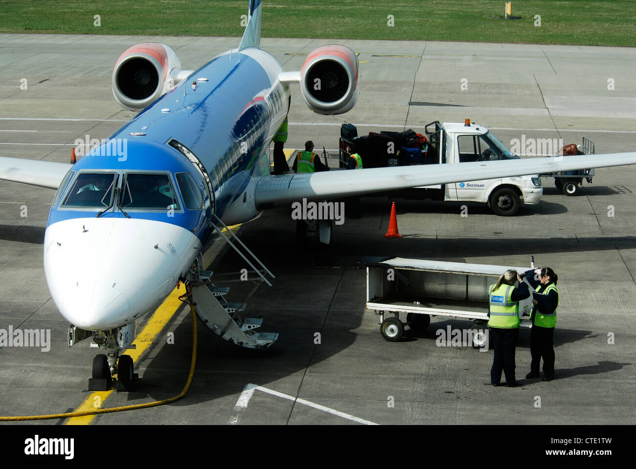BMI Regional Embraer ERJ-145EP de descarga de carga de equipaje en el delantal en el aeropuerto de Edimburgo Foto de stock
