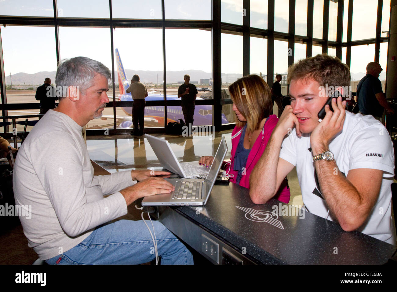 La gente utiliza Internet wi-fi en el Aeropuerto Internacional Phoenix Sky Harbor, ubicado en la ciudad de Phoenix, Arizona, EE.UU. Foto de stock