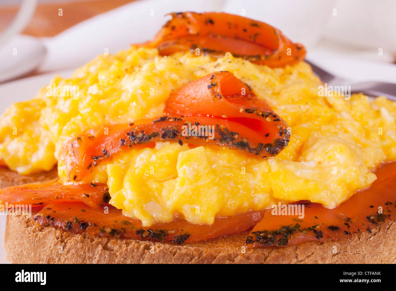 Sazonado de salmón ahumado con huevos revueltos sobre una tostada. Foto de stock
