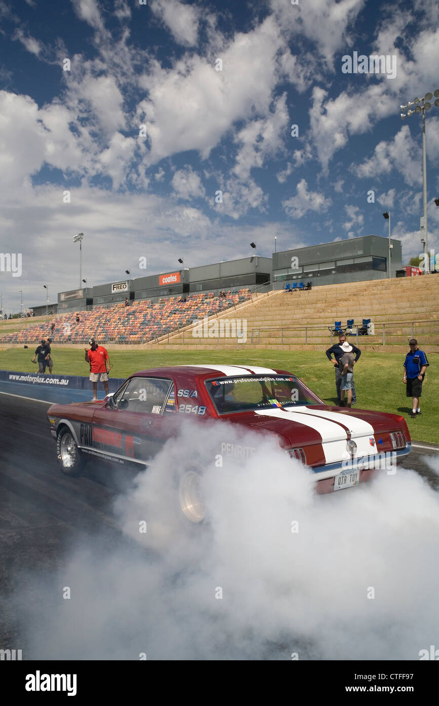 Ford Mustang realizar un neumático neumático tabaquismo burnout para calentar los neumáticos traseros neumáticos antes de las carreras en el cuarto de milla. Foto de stock