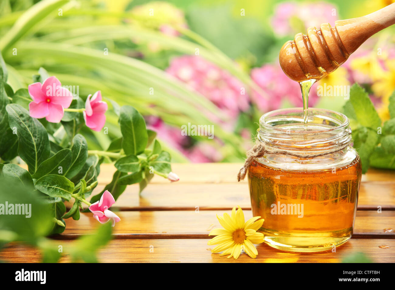 La Miel en tarros de vidrio con flores de fondo. Foto de stock