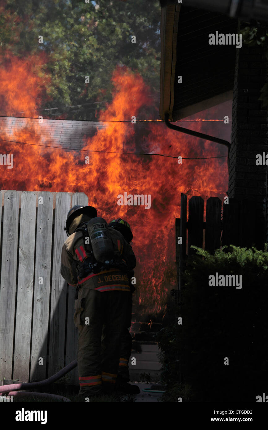 Los bomberos acercarse a un gran garaje fuego detrás de una valla. Foto de stock