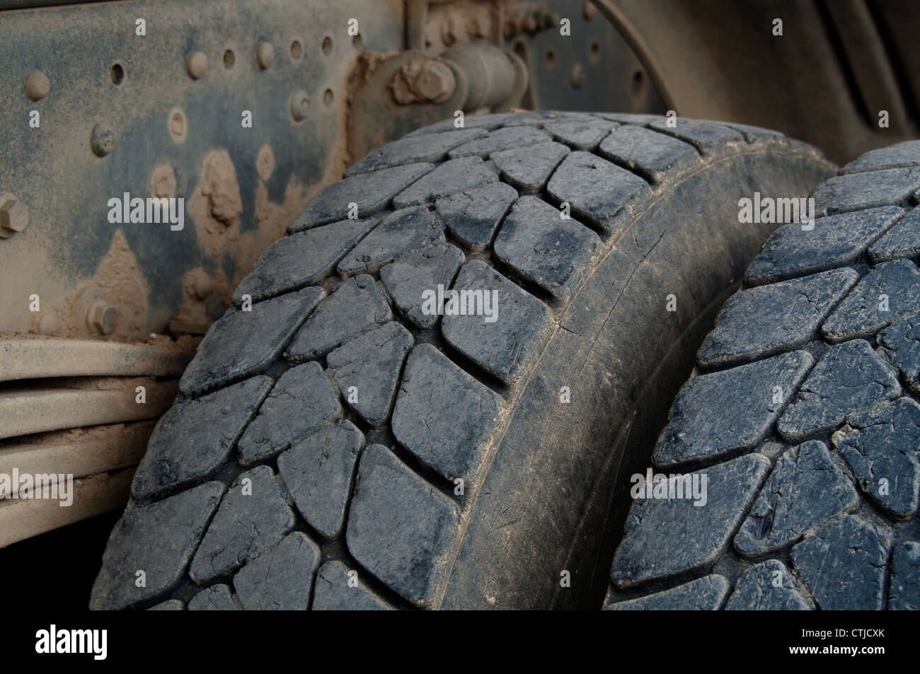 Primer plano de los neumáticos grandes y suspensión de un sucio camión volquete Foto de stock