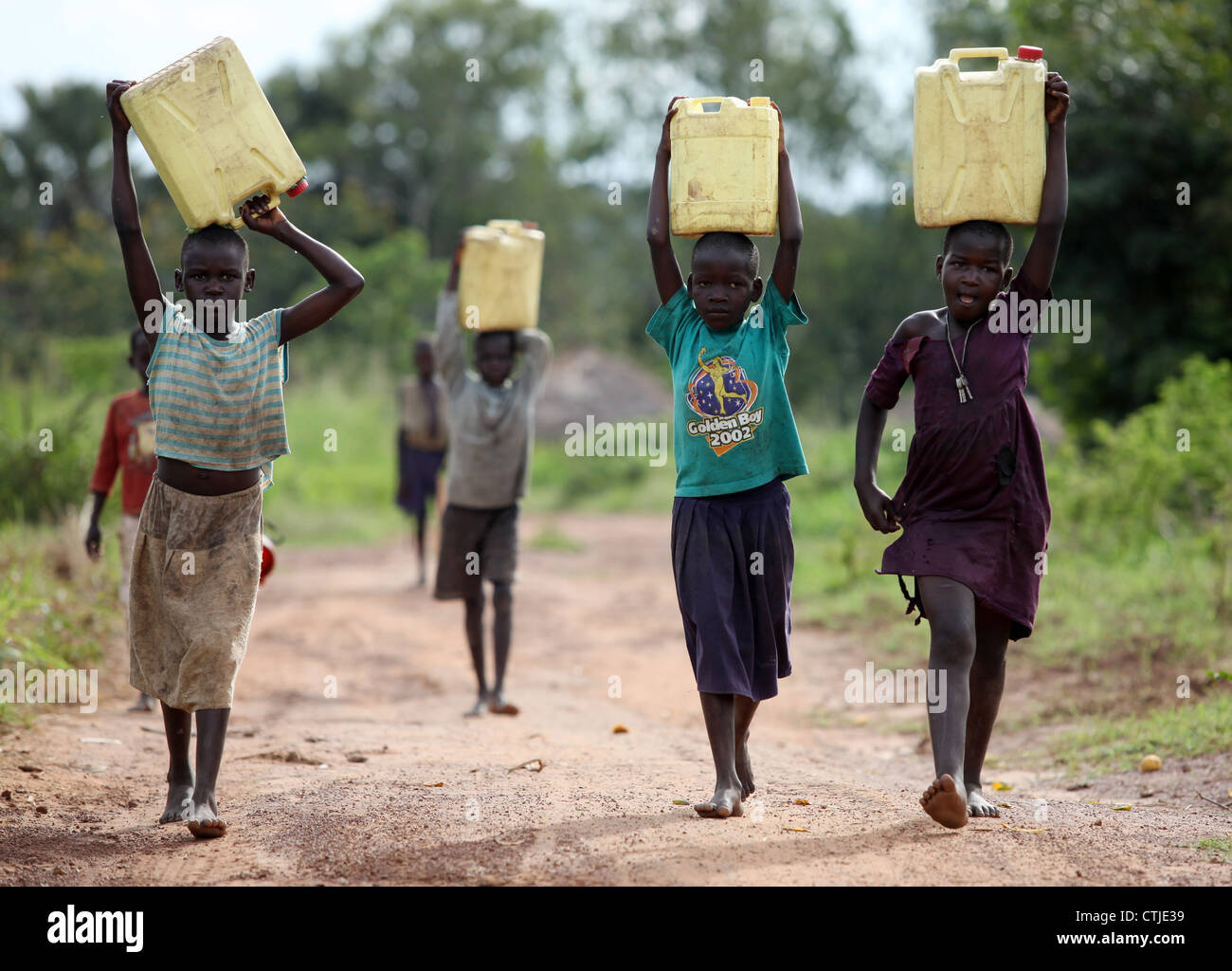 Los niños de la aldea joven termine su día recolectando agua sucia para sus familias en el distrito de Lira, en el norte de Uganda Foto de stock