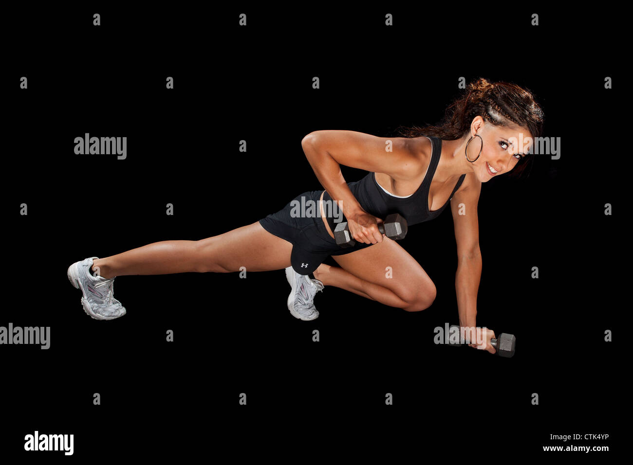 Ejercicio fitness bailarina pulse arriba haciendo ejercicio con pesas modelo deportivo contra el fondo negro iluminación de estudio. Foto de stock