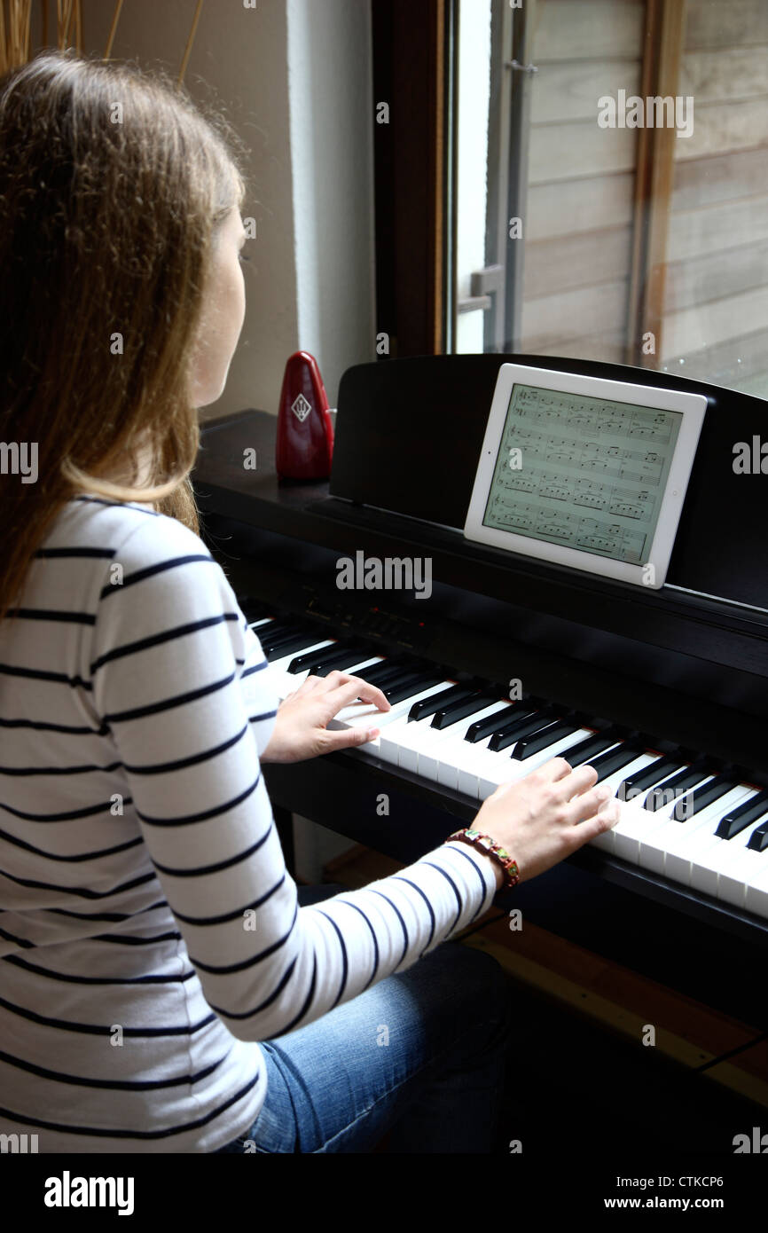 Niña jugando en el piano, la lectura de las notas de una IPad, tablet pc  Fotografía de stock - Alamy