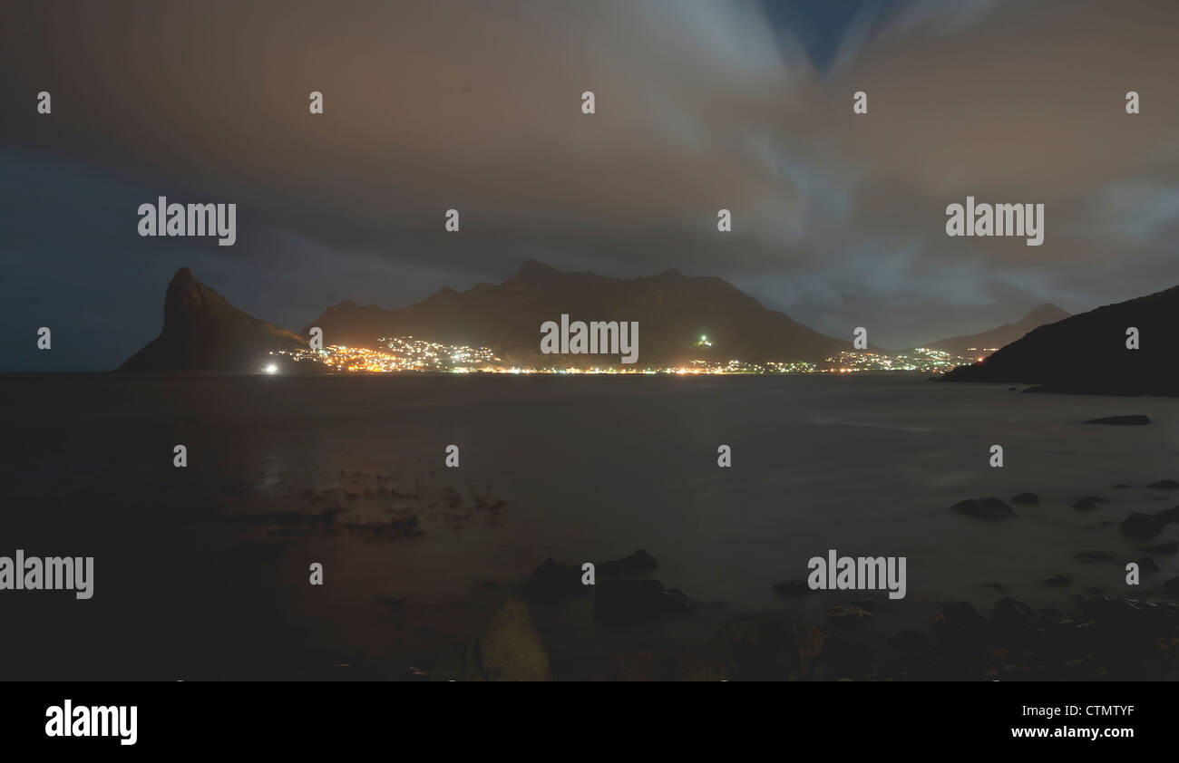 Hout Bay Harbour y centinela visto desde Tintswalo Atlantic lodge por la noche, en Ciudad del Cabo, Sudáfrica Foto de stock