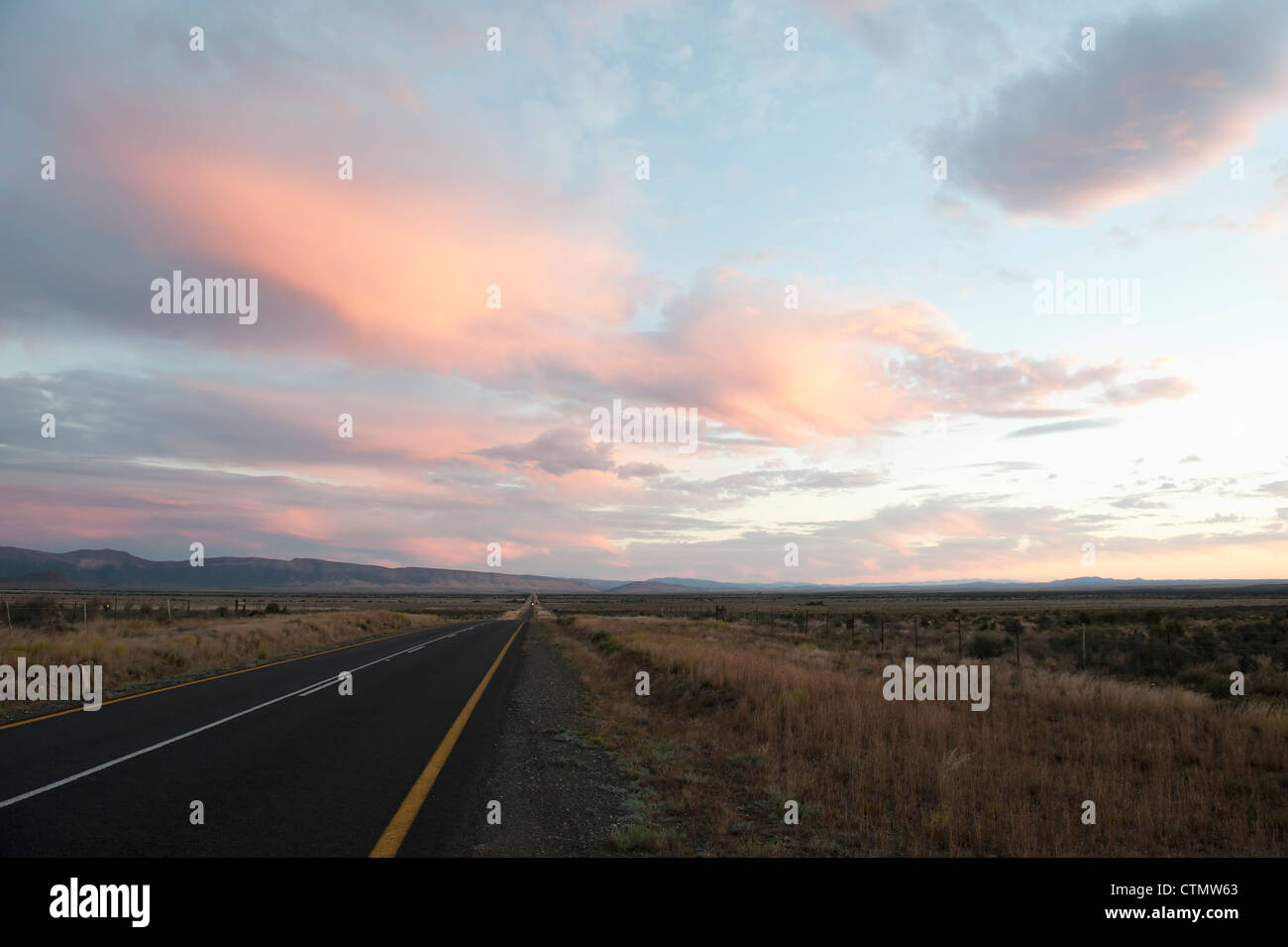El largo camino: Los viajeros que llegan al atardecer en el Gran Karoo, Sudáfrica Foto de stock