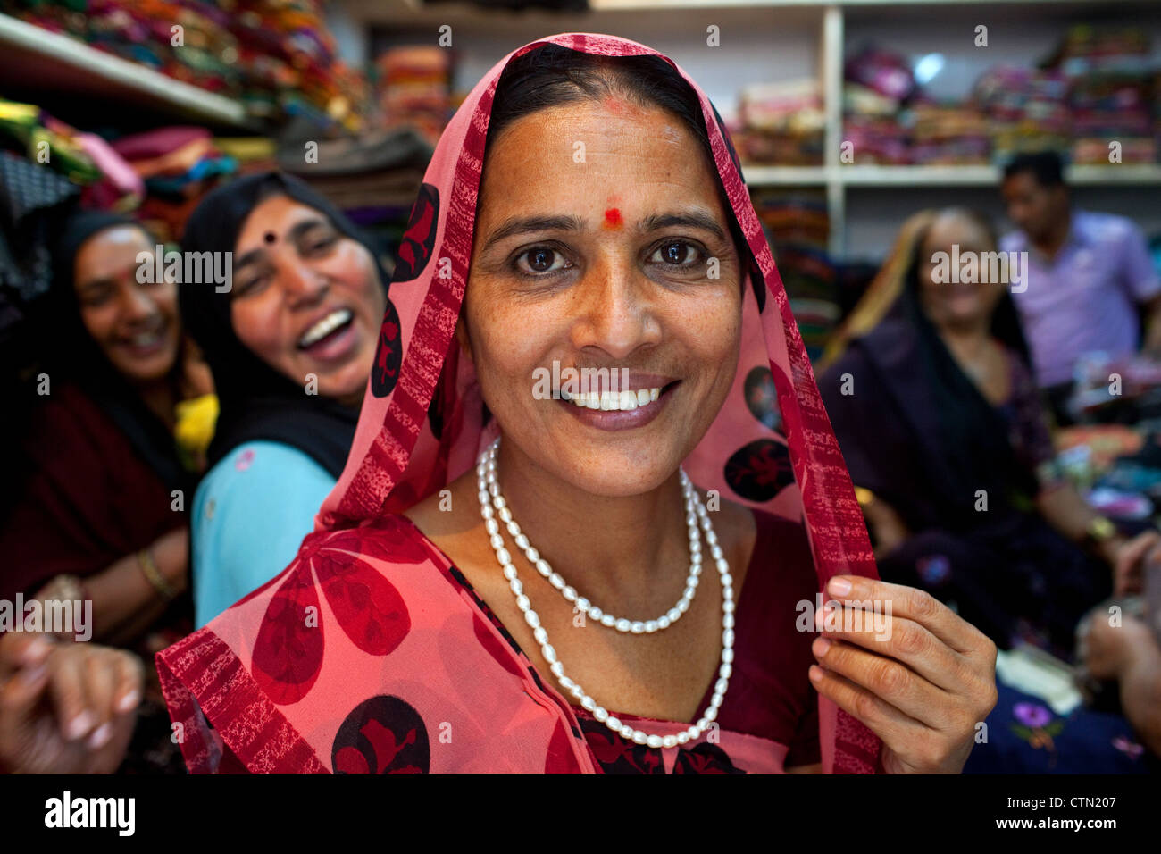 Un retrato de la sonrisa bastante Rabari mujeres vistiendo ropa sari tradicional en una tienda textil en Ahmedabad, estado de Gujarat, India. Foto de stock