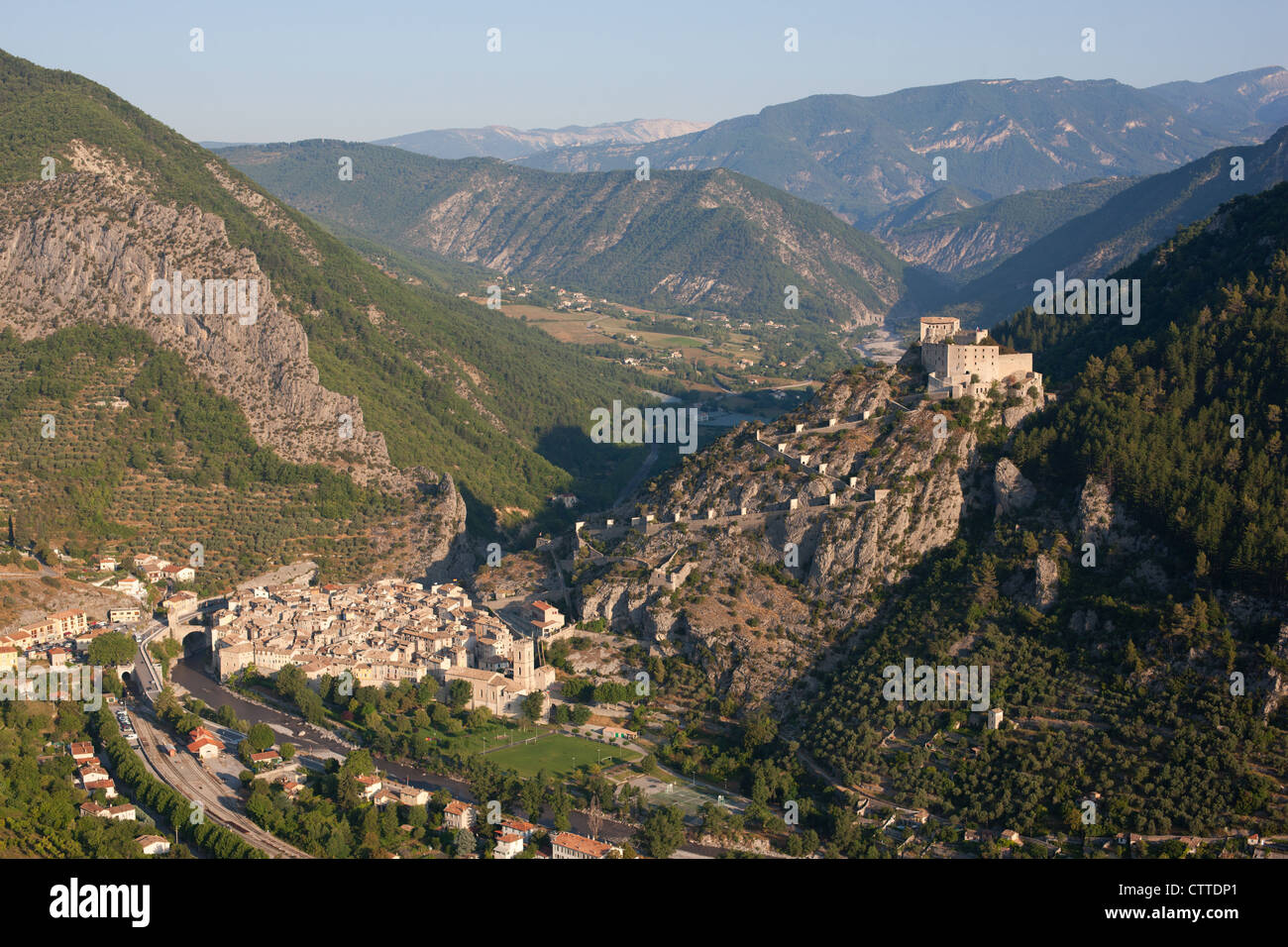 VISTA AÉREA. La ciudadela de Entrevaux dominada por su castillo en un paso estratégico estrecho en el valle de Var, Alpes de Alta Provenza, Francia. Foto de stock