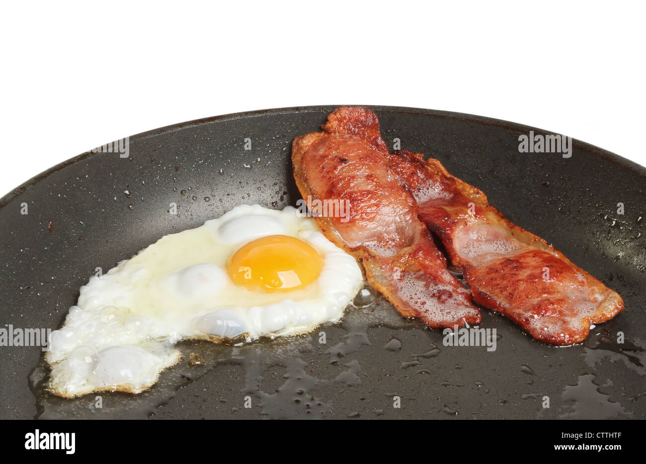 Huevo y tocino friéndose en una sartén Foto de stock