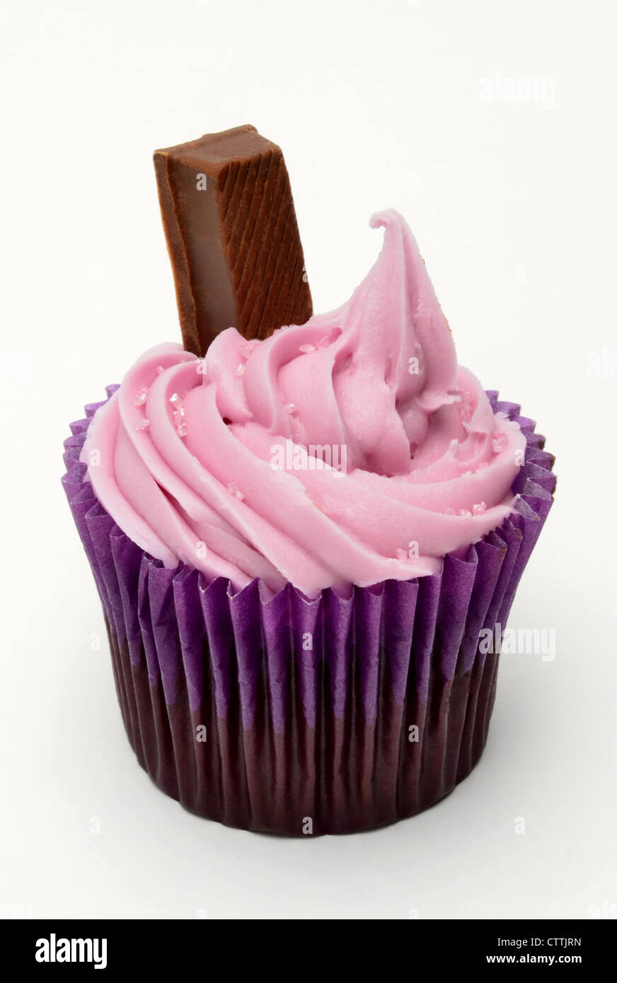 Cupcake con glaseado rosa y chocolate dedo contra un fondo blanco. Foto de stock