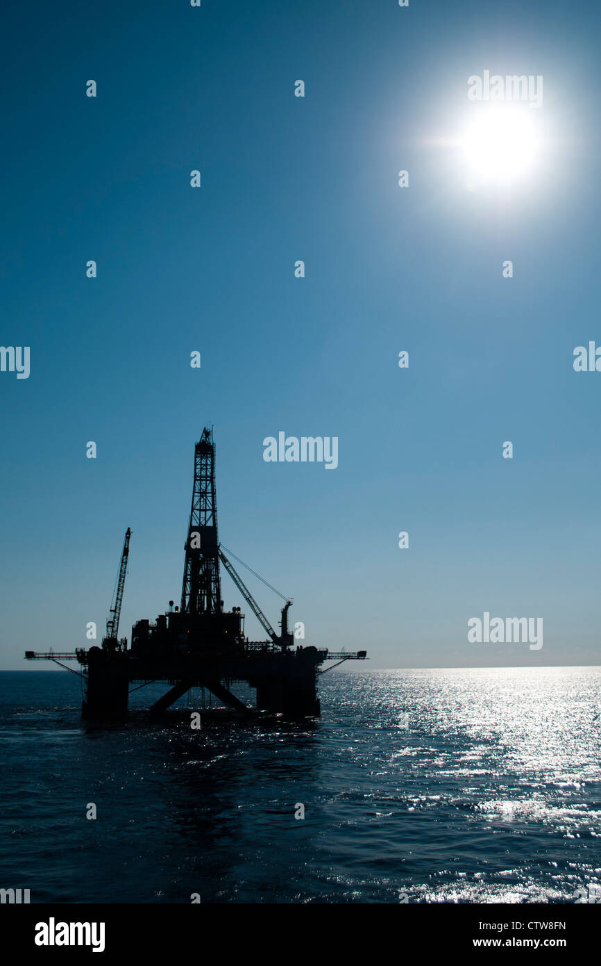 Silueta de una plataforma petrolífera en alta mar en la zona oceánica. Foto de stock