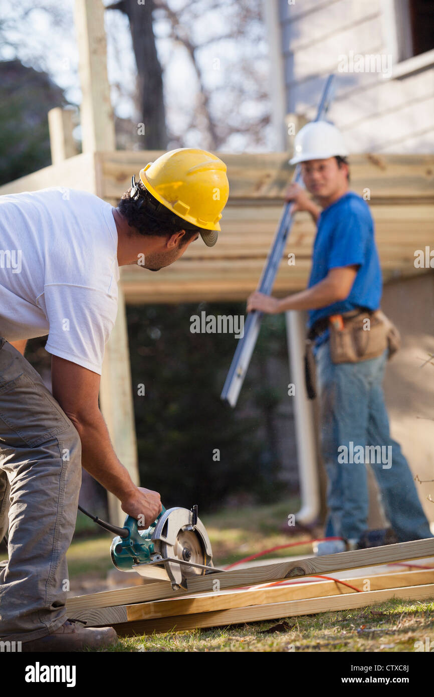 Carpinteros usando una sierra circular en casa construcción de la cubierta Foto de stock