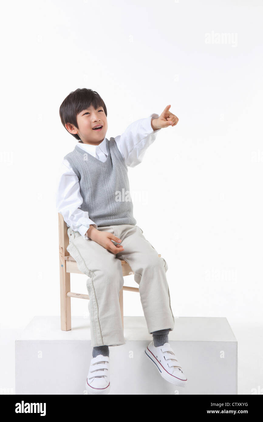 Un niño señalando al cielo en la silla Foto de stock
