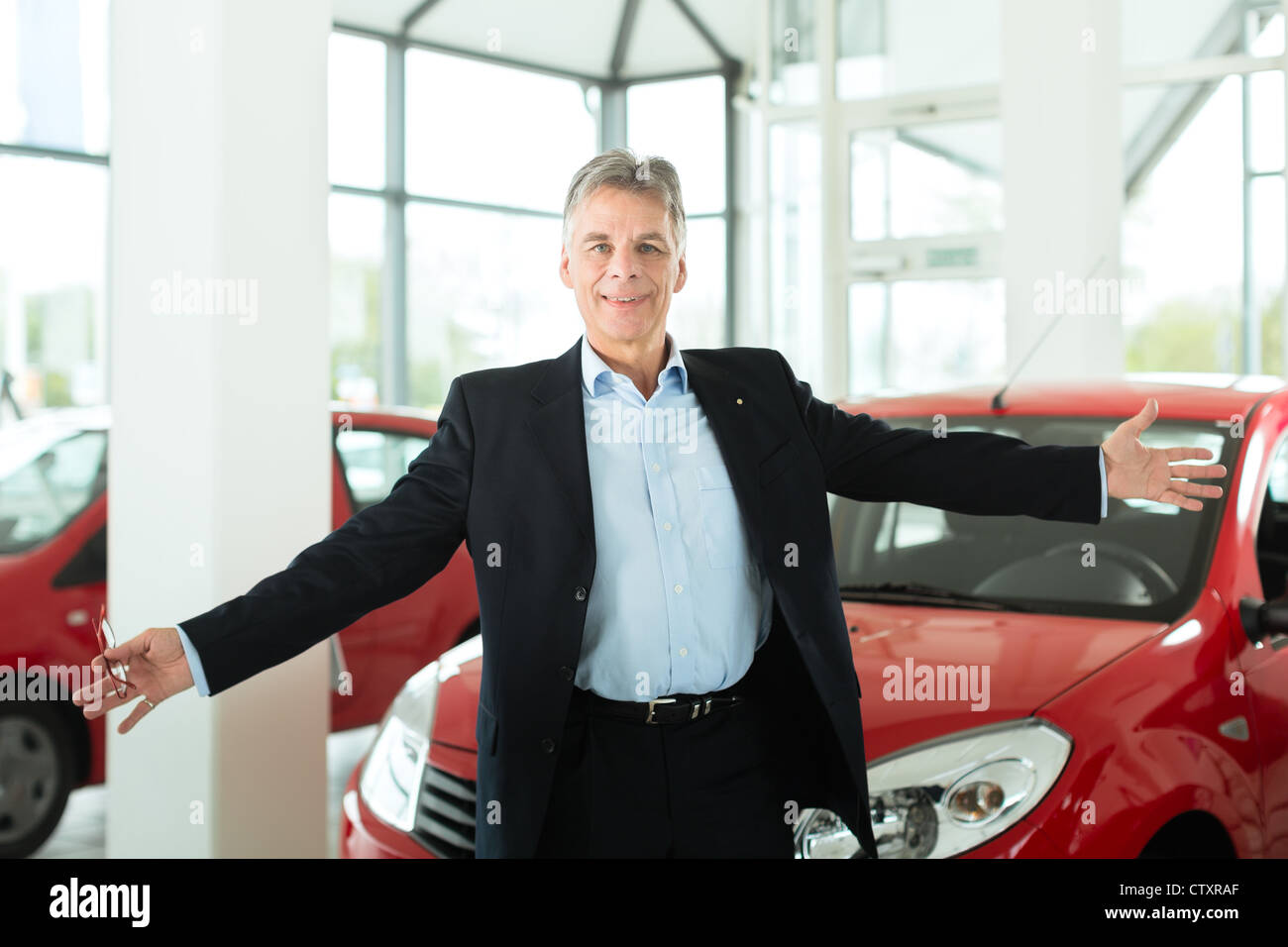 Un hombre maduro con luz roja en auto concesionario de automóviles, él es, obviamente, la compra de un coche o un concesionario de coches Foto de stock
