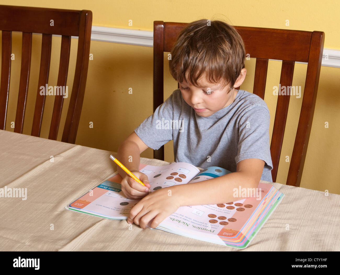 Mexicano Americano de 7 años de edad escolar boy hace tareas de matemáticas utilizando los dedos para contar en casa Foto de stock