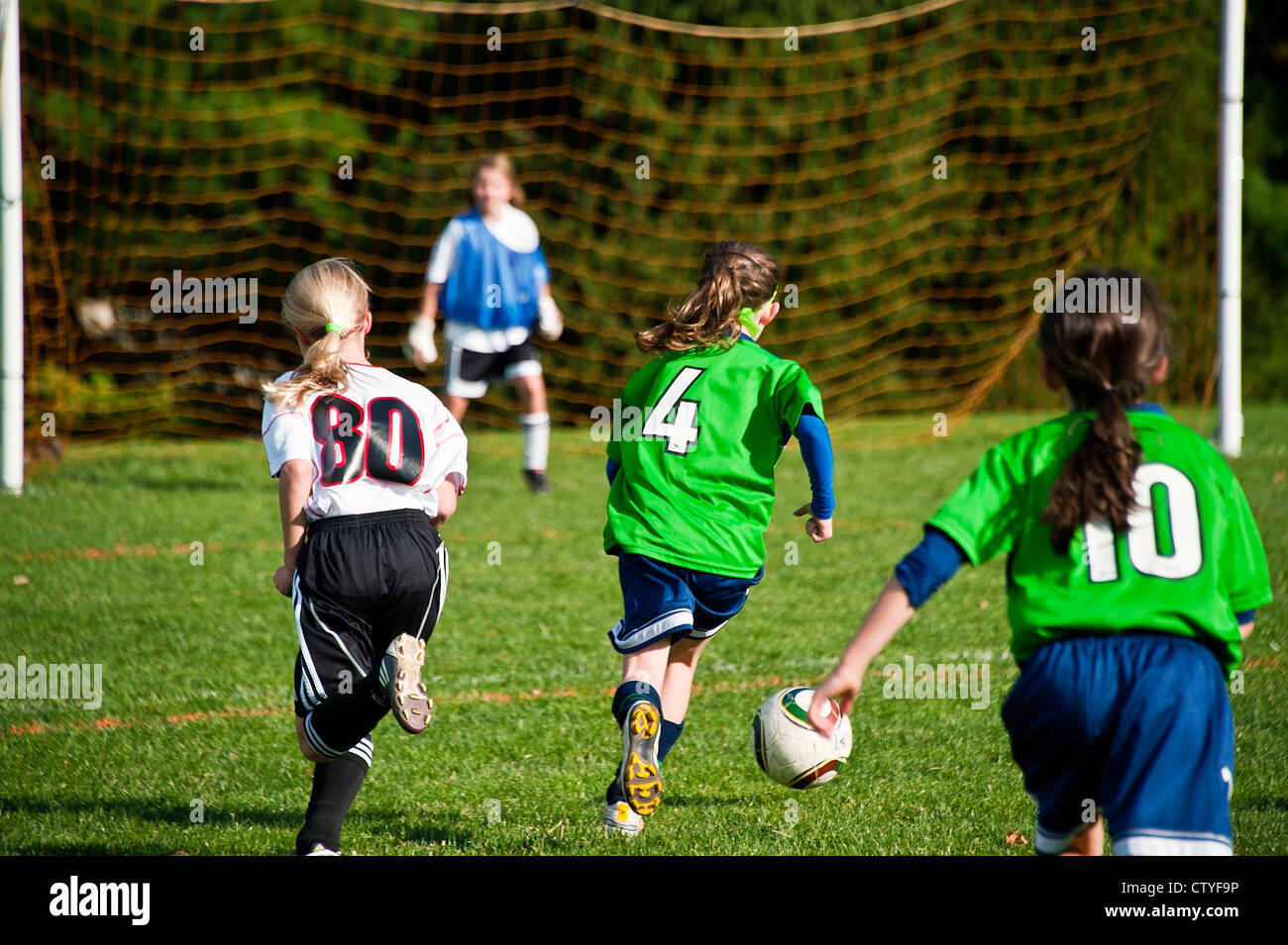 Chica de fútbol juvenil regatea un balón de fútbol a la meta. Foto de stock