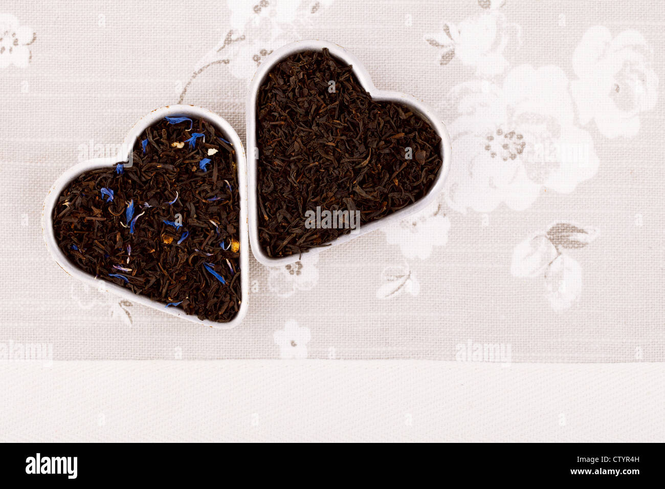Earl Grey y Lady Grey Negros Aflojan las hojas de té en forma de corazón, sobre lino Foto de stock