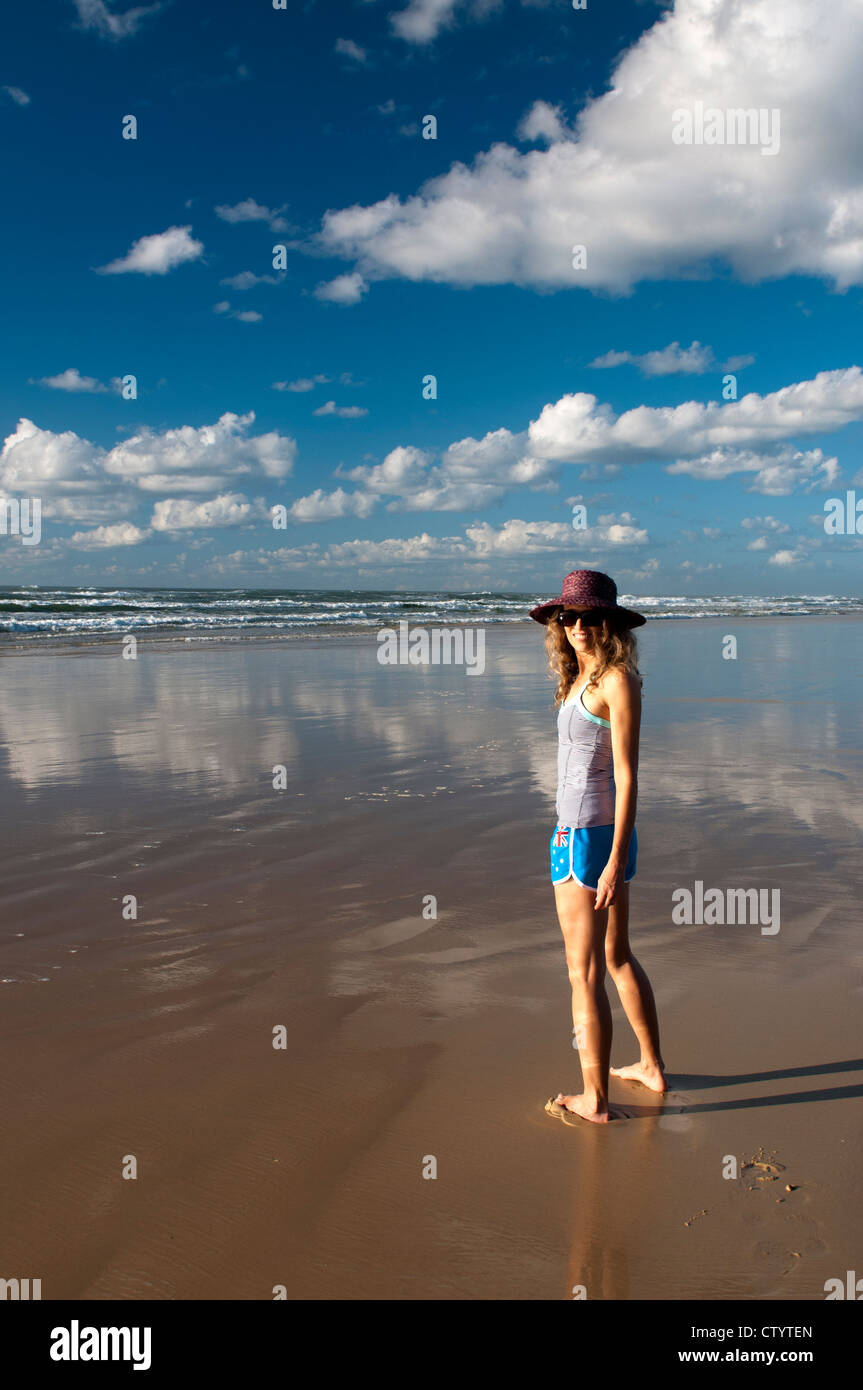 Mujer de pie sola en una playa en un día soleado. Foto de stock