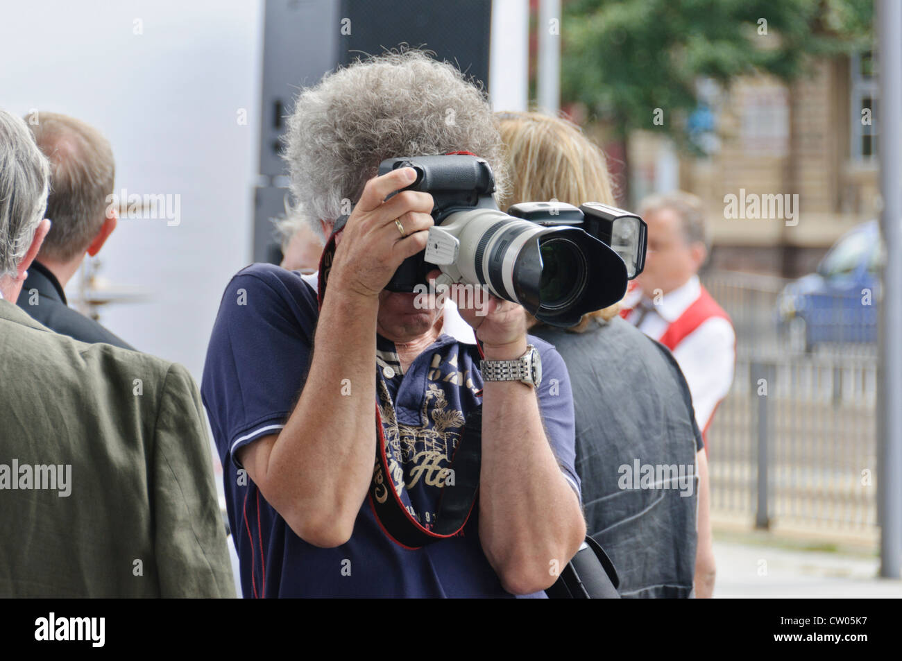 El adulto maduro hombre caucásico con gris pelo rizado, macho profesional fotógrafo, tomando fotos con una cámara DSLR de fotograma completo de Canon Foto de stock