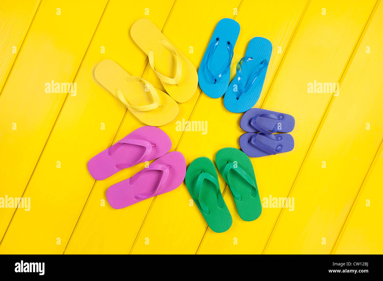 Una variedad de coloridas chanclas de goma en un patrón circular sobre una  plancha de madera, piscina cubierta amarilla Fotografía de stock - Alamy