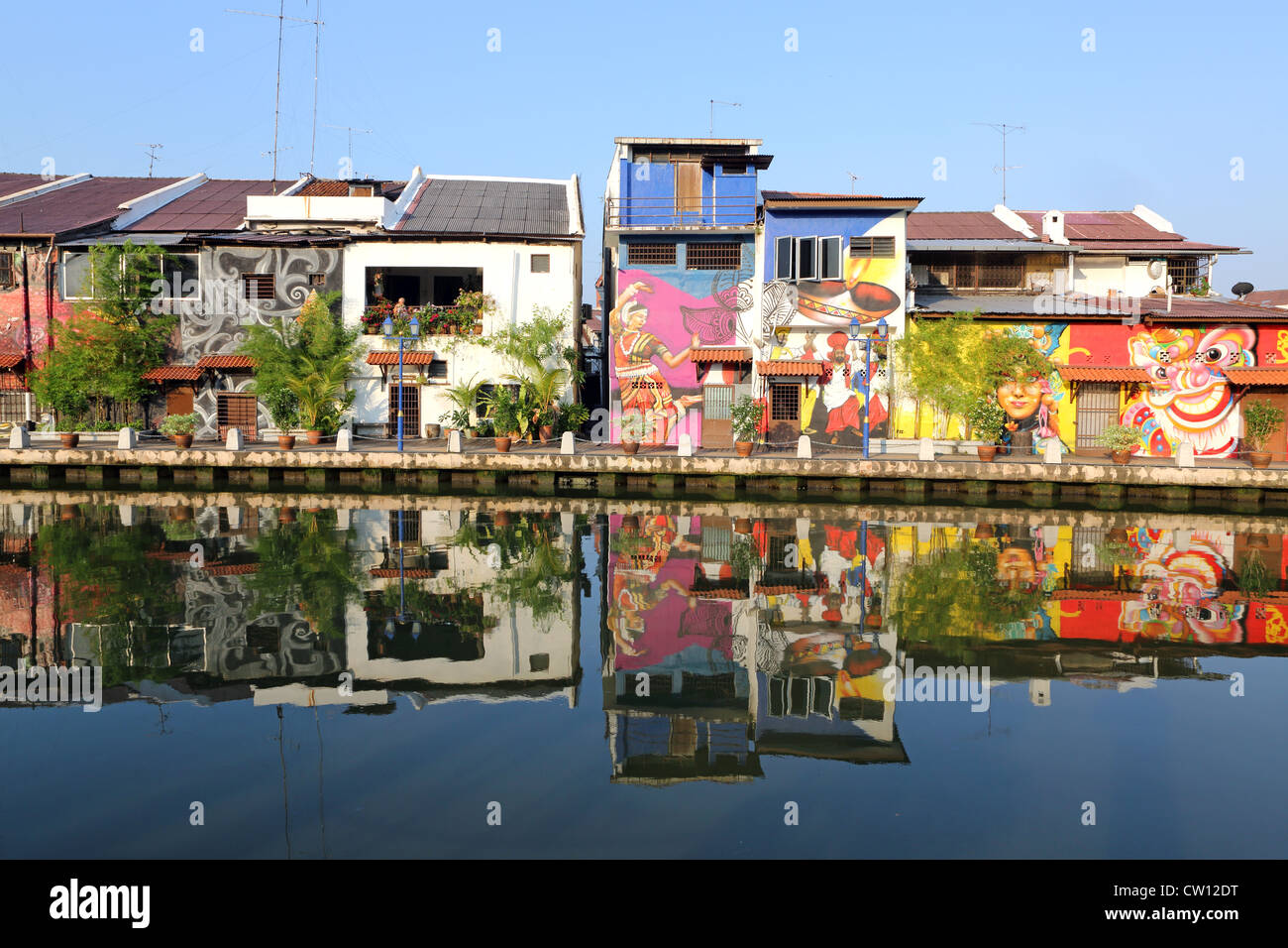 Los edificios patrimoniales de colores brillantes pintados con murales alinean el río Melaka en Melaka, Malasia Foto de stock