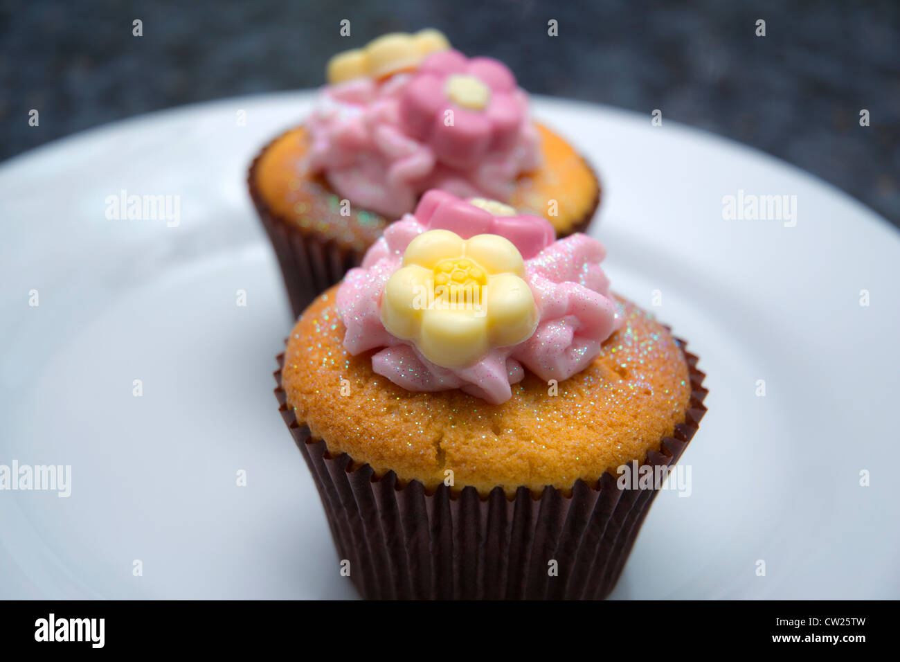 Rosa y amarillo hielo caseras decoradas Cup Cakes en una placa Foto de stock