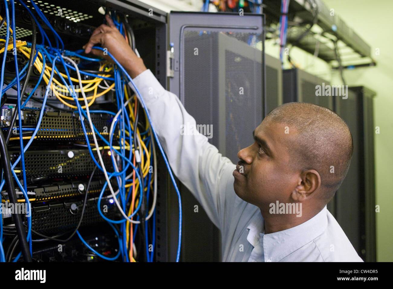 El perfil lateral de un técnico reparando cables de servidor de red Foto de stock