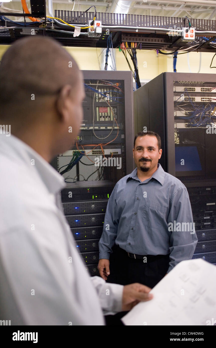 Dos técnicos hablando delante de un servidor de red Foto de stock