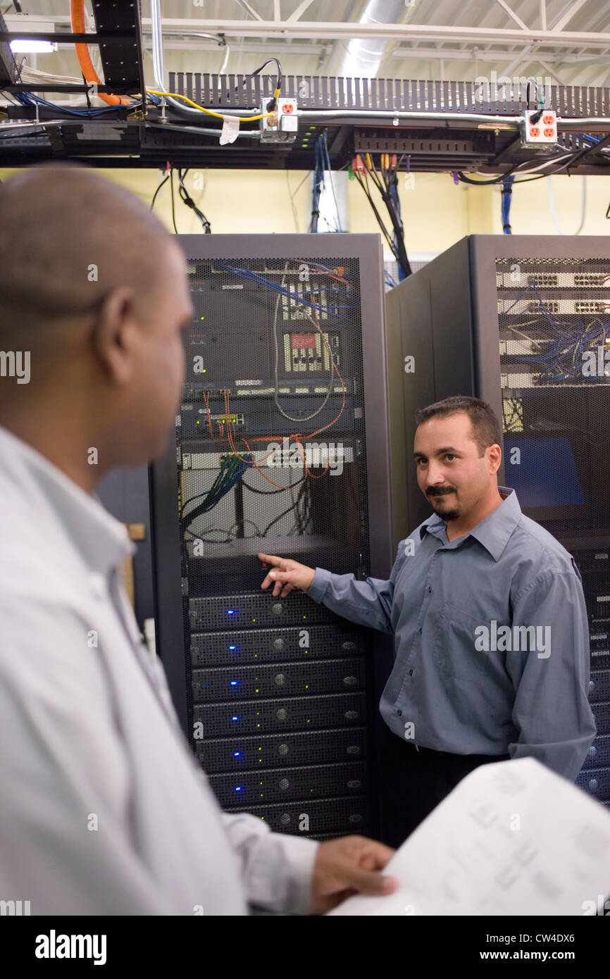 Dos técnicos hablando delante de un servidor de red Foto de stock
