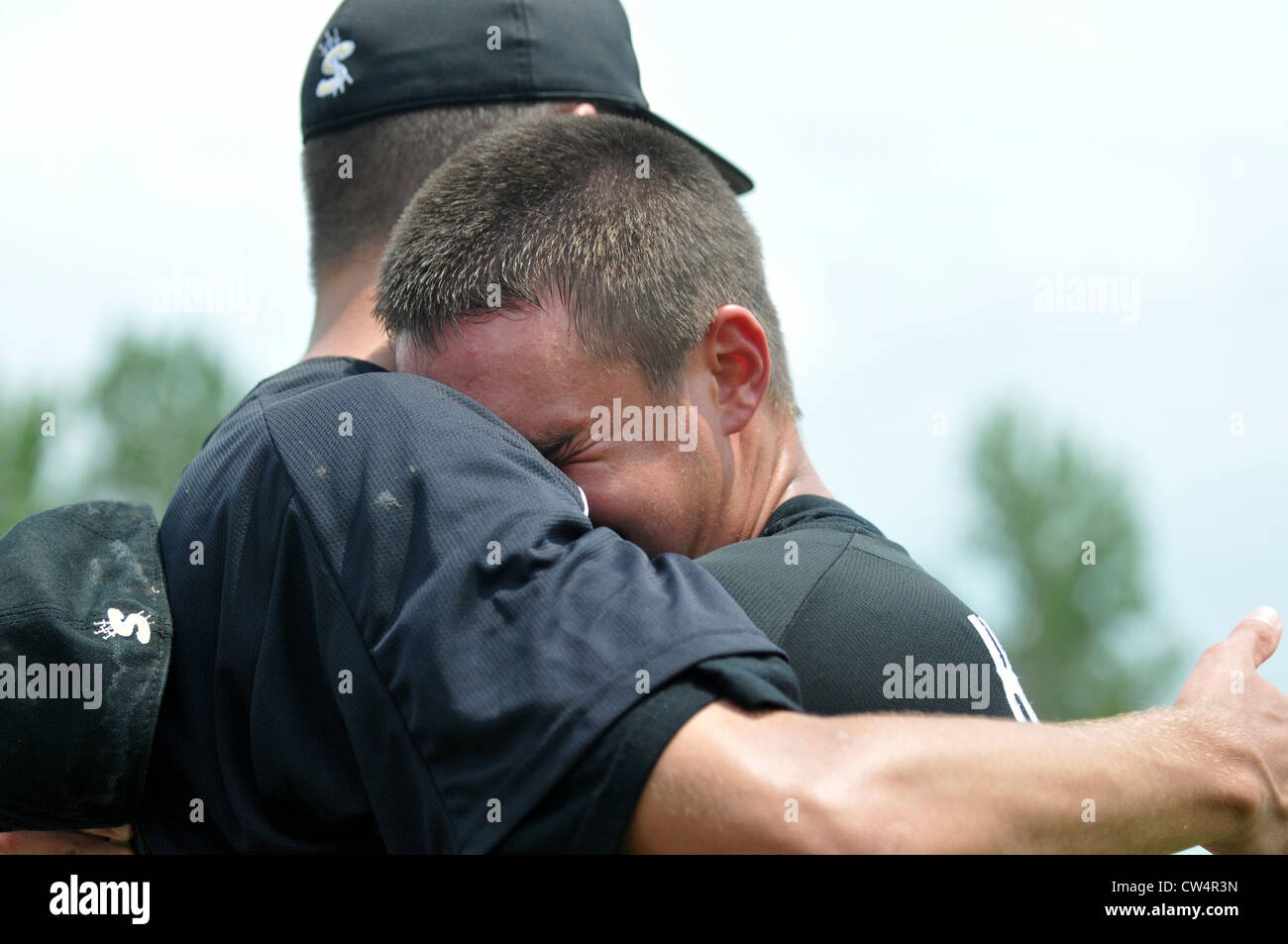 Dos jugadores de béisbol abrazo para celebrar la alegría de la victoria en ganar un campeonato regional high school juego del playoff. Ee.Uu.. Foto de stock