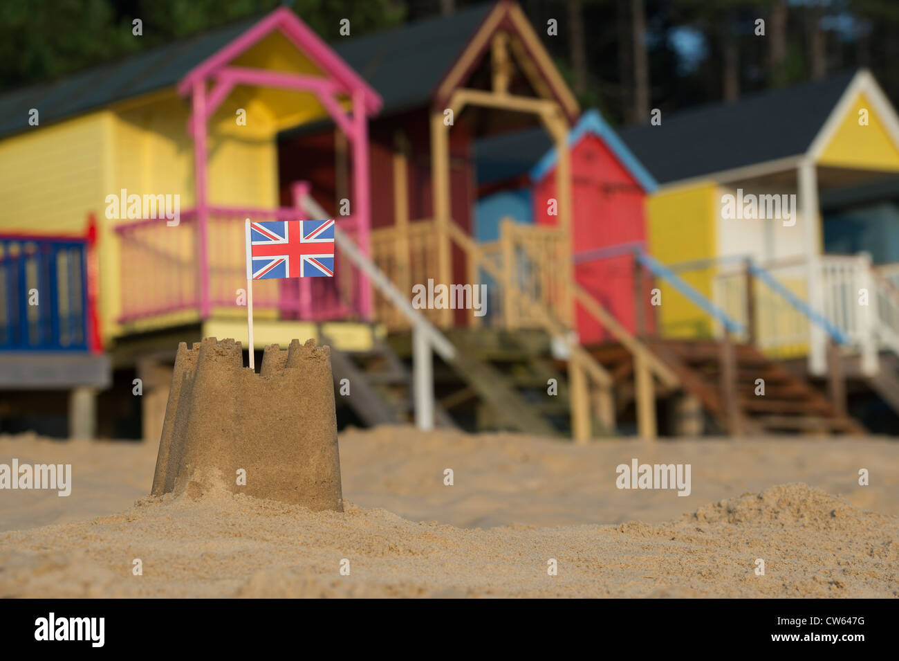 Bandera Union Jack en un castillo de arena en la parte delantera de coloridas casetas de playa. Wells junto al mar. Norfolk, Inglaterra Foto de stock