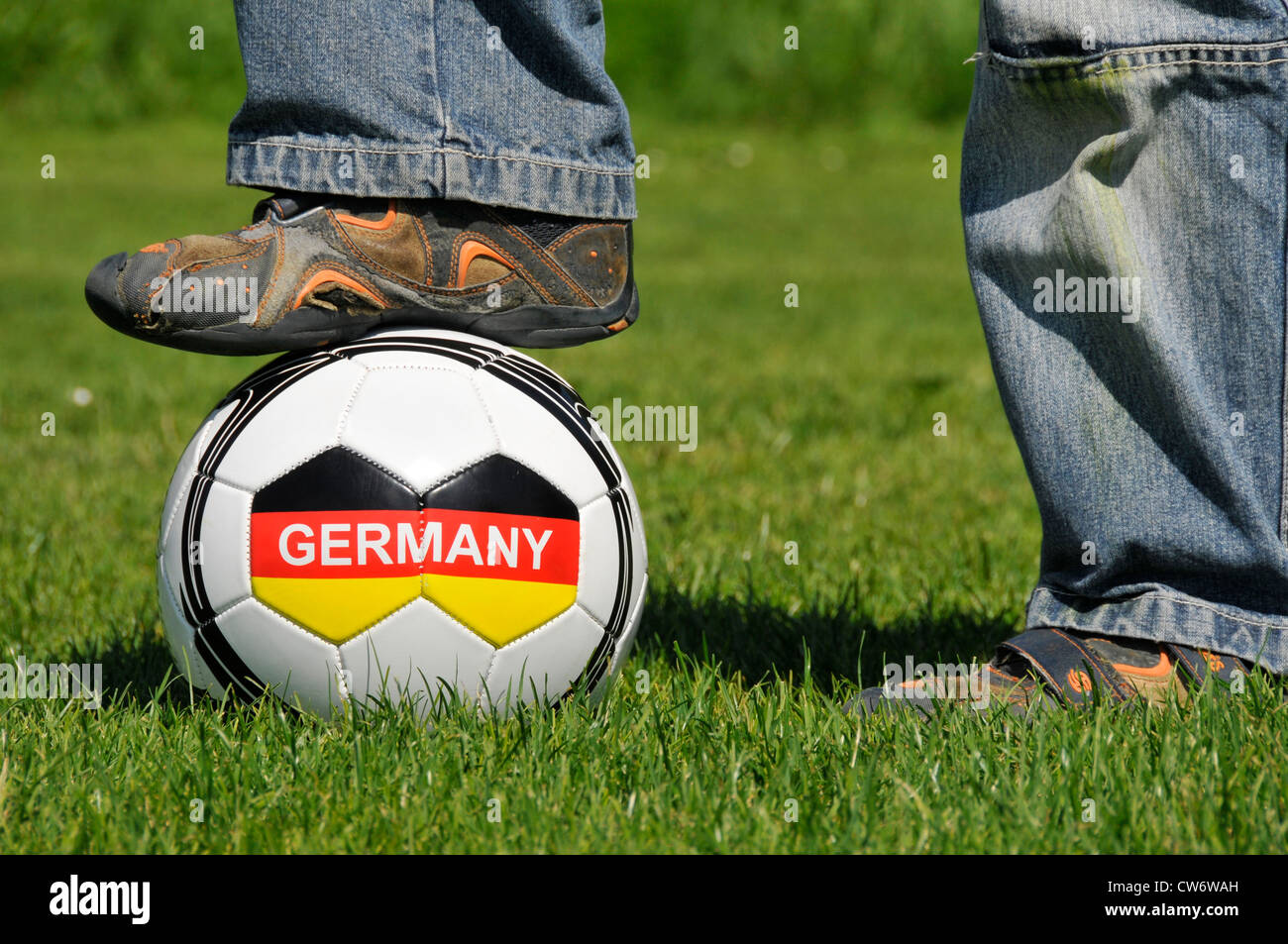 Un muchacho de pie sobre una pelota de fútbol con la escritura 'Alemania', Alemania Baden-Wurtemberg Foto de stock