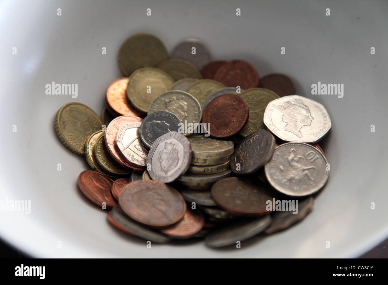 Es una foto de un recipiente blanco lleno de monedas. Podemos ver la libra inglesa dinero que están allí. Puede ser consejos o dinero de bolsillo Foto de stock