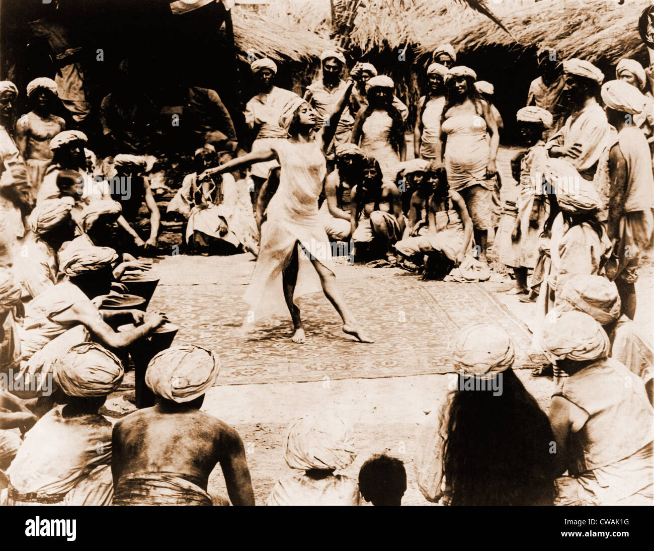 Nautch chica, un joven indio sobre la alfombra de baile hindú con hombres y mujeres mirando. India, 1914. Foto de stock