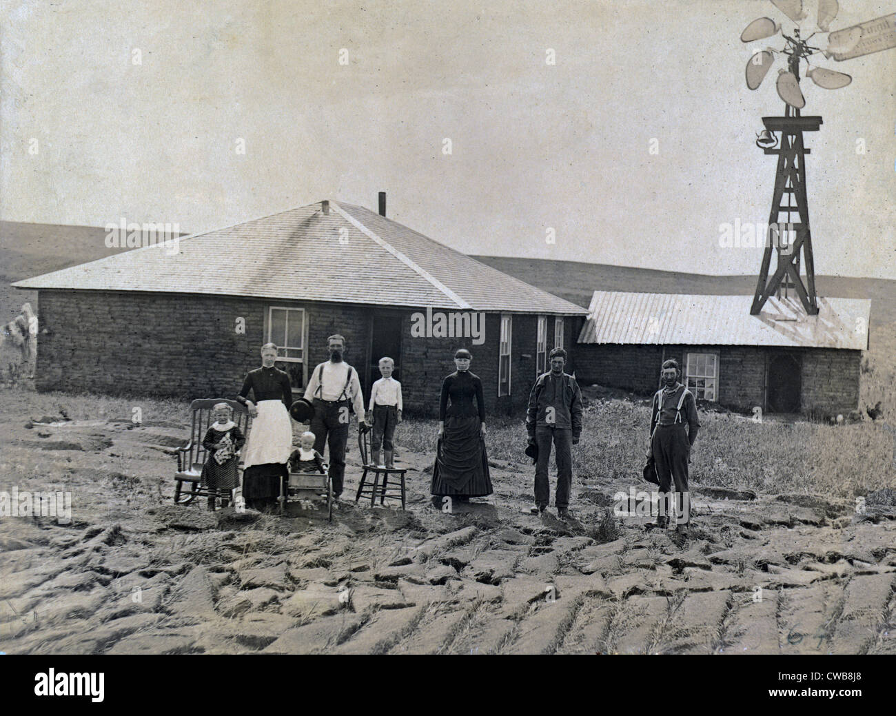Una familia de agricultores de pie en frente de la casa de turba y el molino de viento. Coburg, Nebraska 1885 Foto de stock