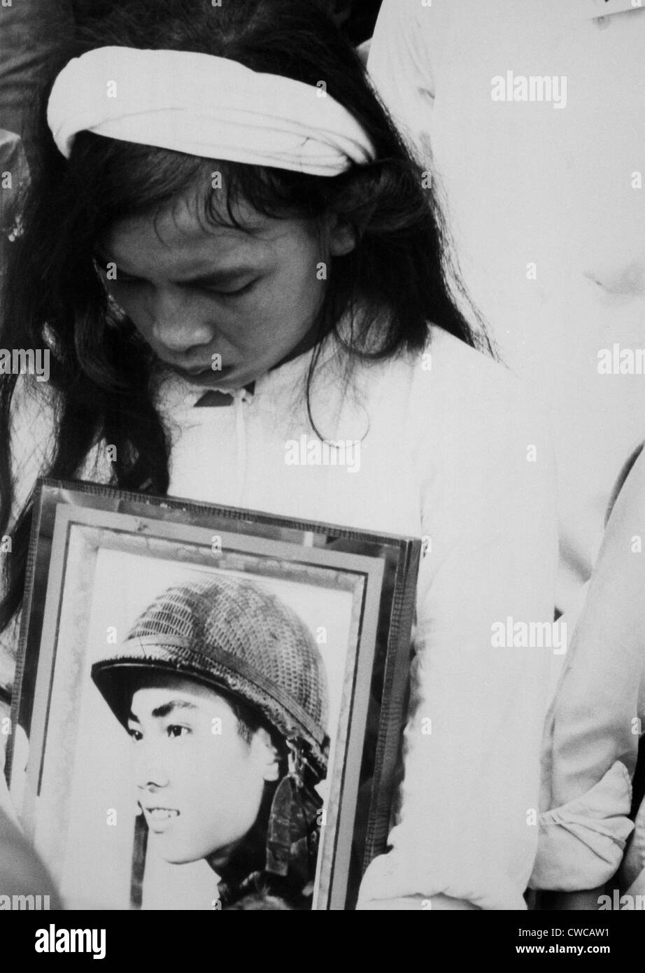 Una joven vietnamita viuda llora. Abrazando una foto de su marido ausente, asiste a una misa funeral por 400 muertos en Foto de stock