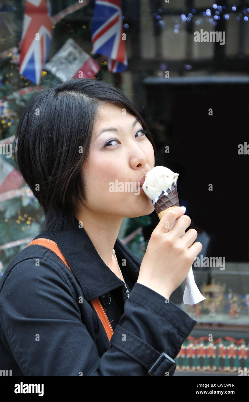 Jovencita japonesa comiendo un helado de vainilla de un cono de chocolate, Stratford upon Avon, Inglaterra, Reino Unido. Foto de stock