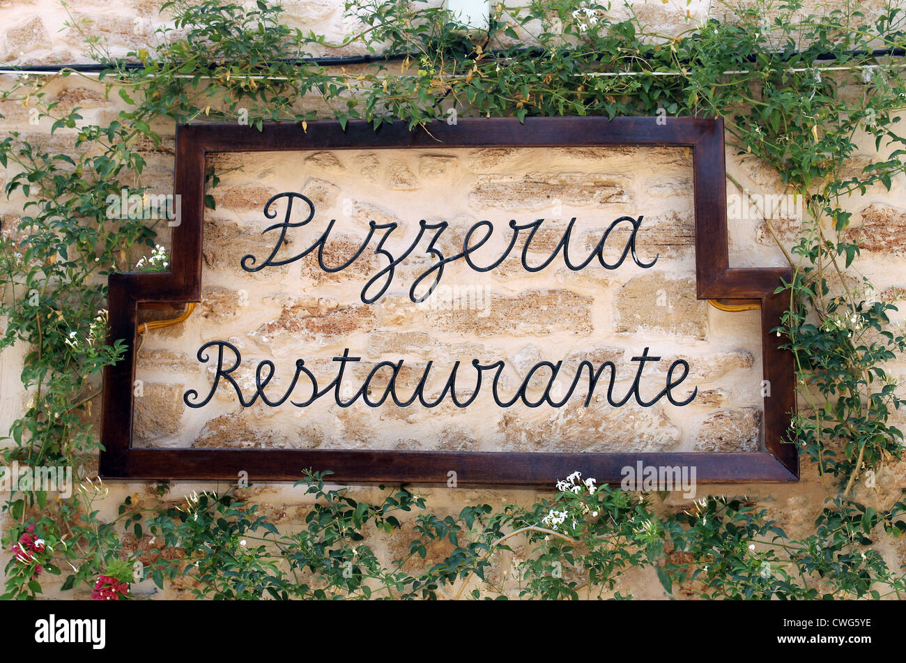 Restaurante Pizzería firmar sobre la antigua muralla rodeada de hiedra, Italiano o Español. Foto de stock