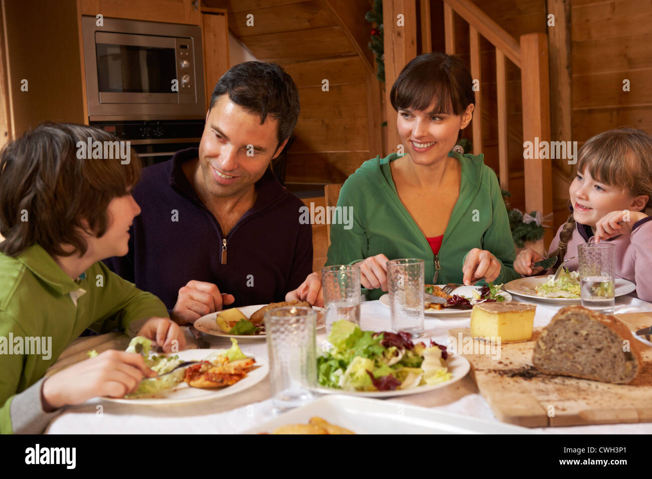 Familia disfrutando de comida en chalet alpino juntos Foto de stock