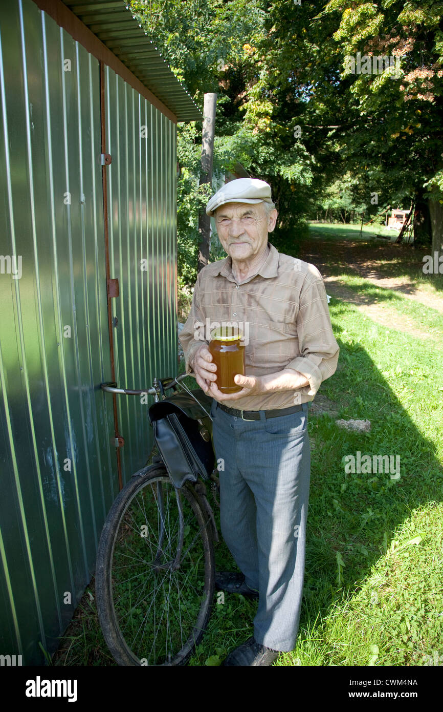 Apicultor polaco, miel o agricultor apiarist, sosteniendo tarro de miel en su bicicleta de ruta de entrega. Zawady Polonia Central Foto de stock