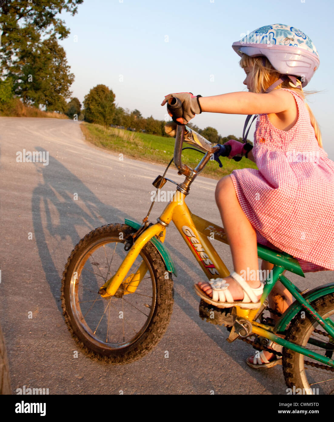 Bicicleta niña de 4 años de edad en el vestido rosado y el casco de  bicicleta Equitación en country road Zawady Polonia Central Fotografía de  stock - Alamy