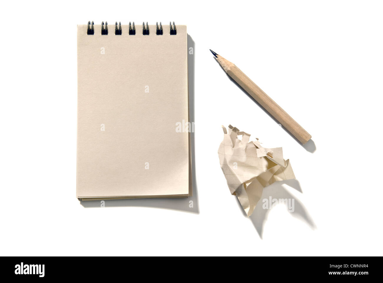 El bloc de notas con un lápiz y un pedazo de papel arrugado, aislado sobre fondo blanco 100% Foto de stock