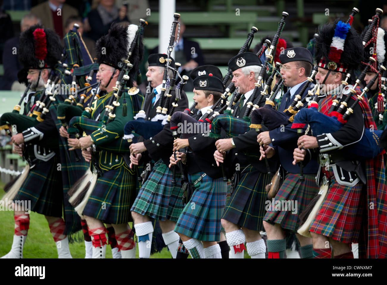 La masificada pipe band desfilan en el campo de deportes en la carrocería durante el Braemar Highland Games. Foto de stock