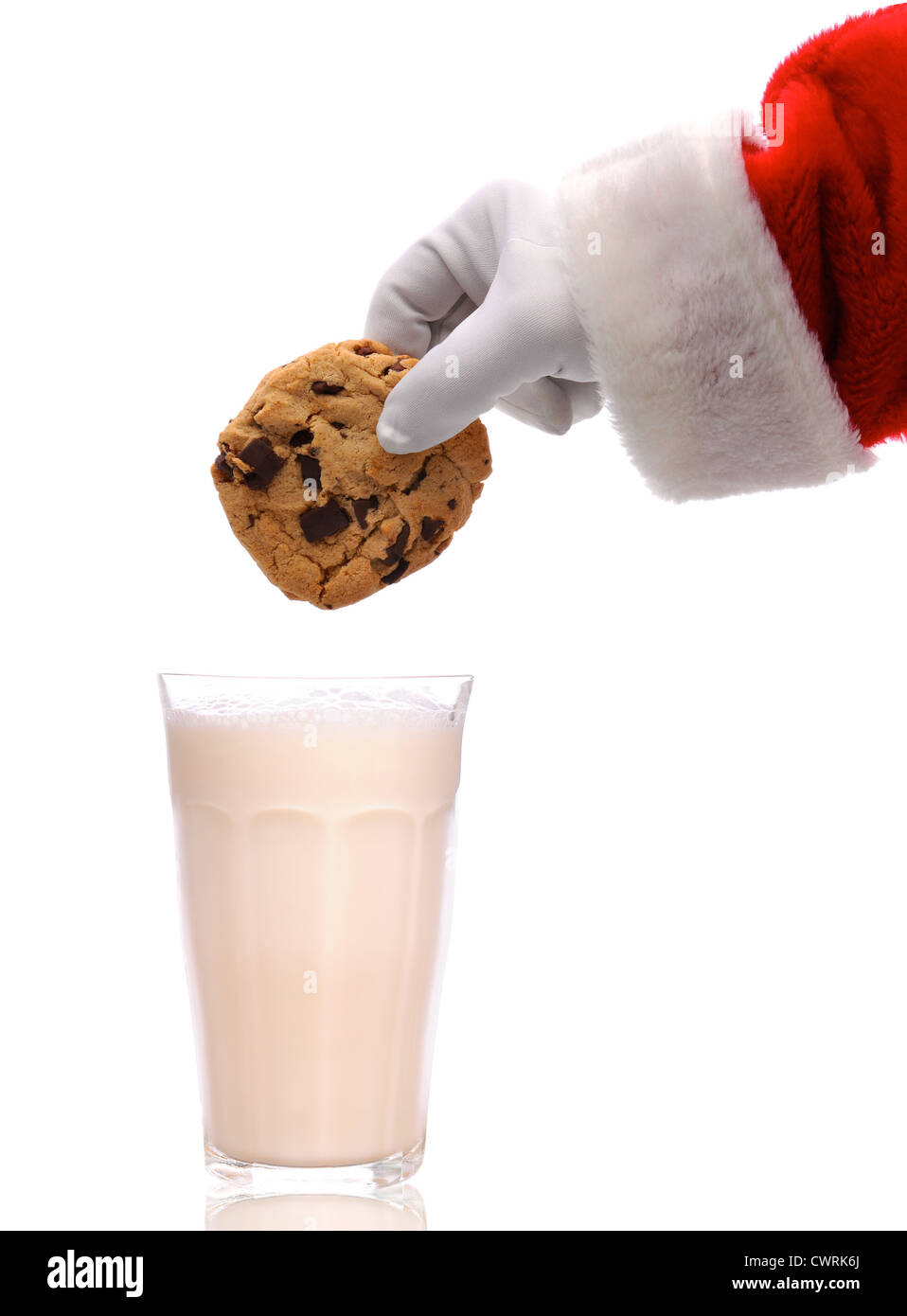 Santa Claus acerca a dunk una galleta de chocolate en un vaso de leche sobre un fondo blanco. Foto de stock