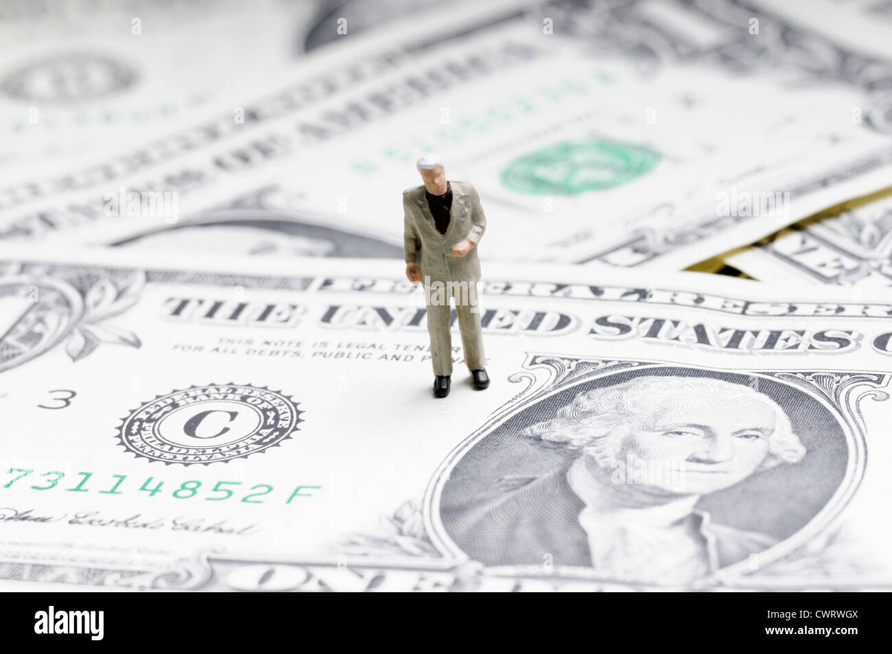 Diminuta figura del empresario de pie sobre un billete de dólar Foto de stock