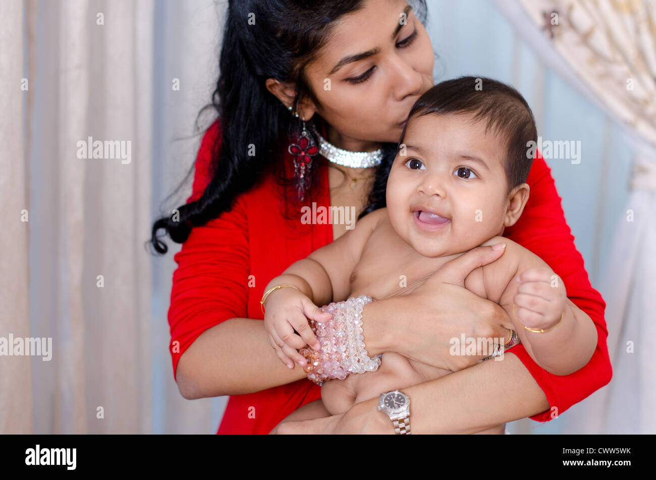 Madre India besando a su hija, interior Foto de stock